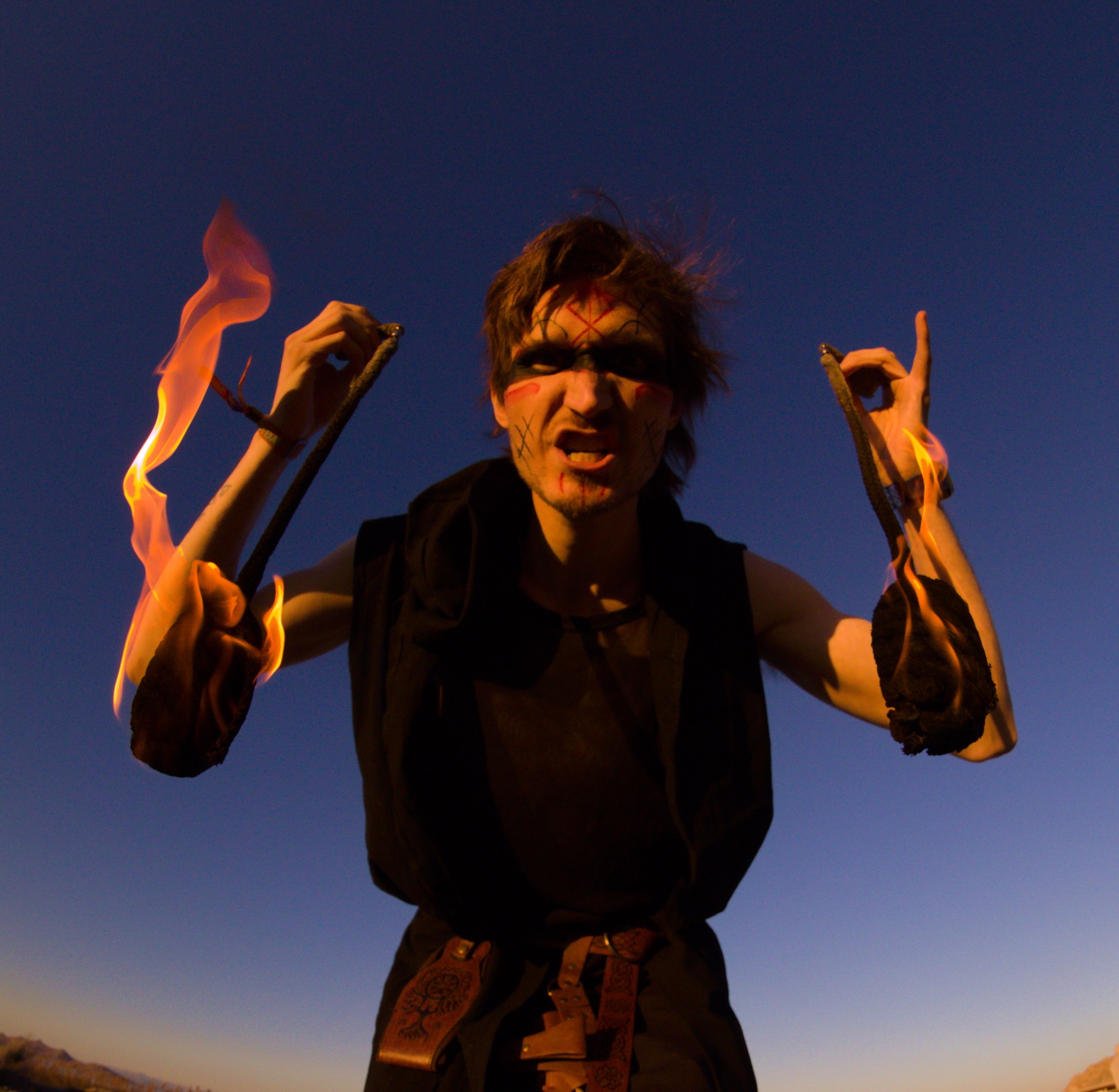 Performer with fire poi at sunset